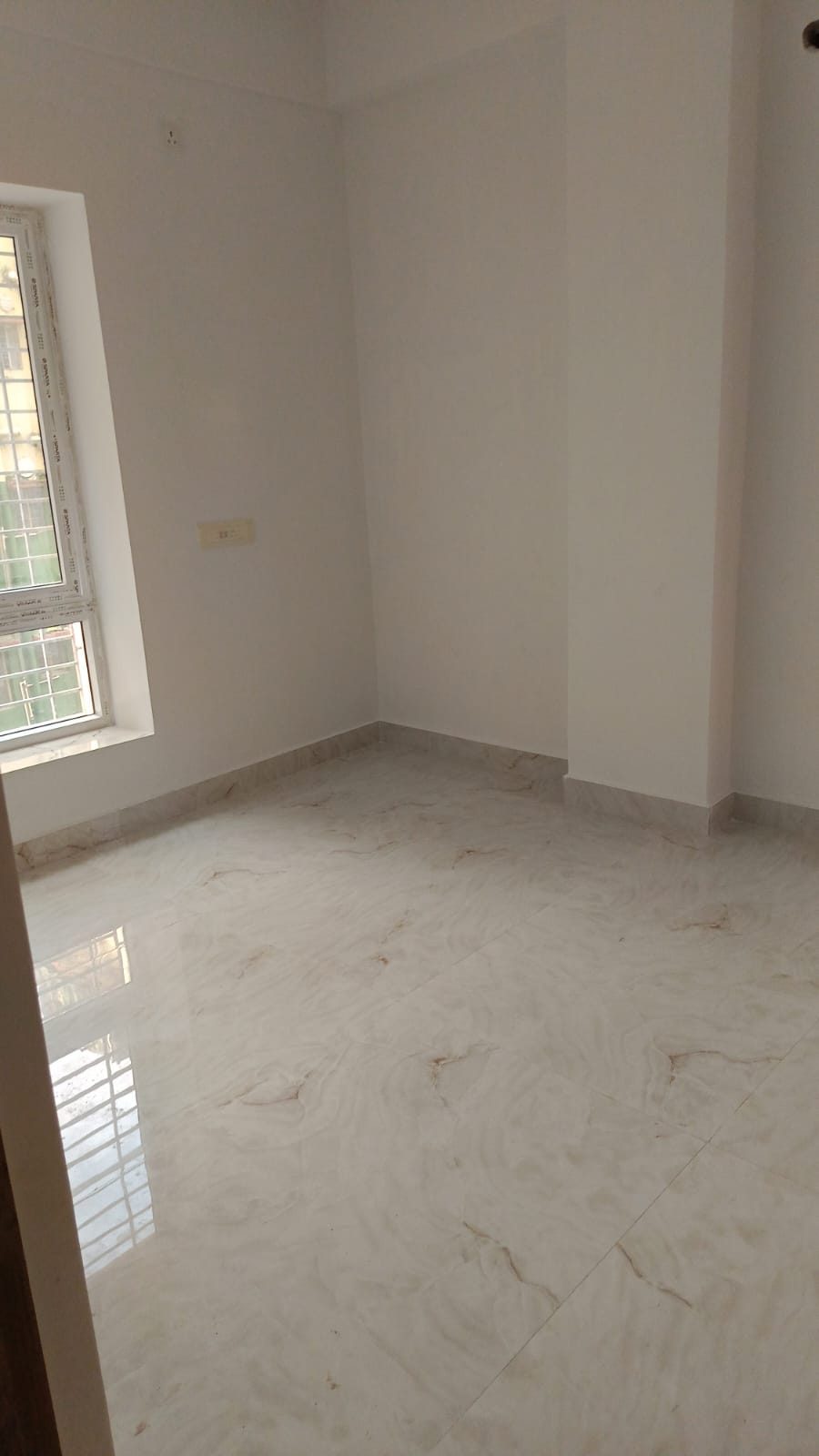 Empty room with a window and polished marble floor at Krishna Kamdhenu, Kestopur
